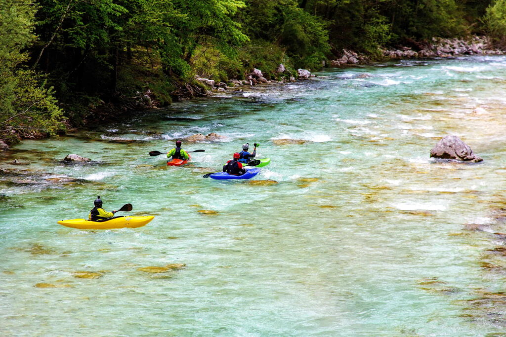 A group of four people rafts over rapids in a river.